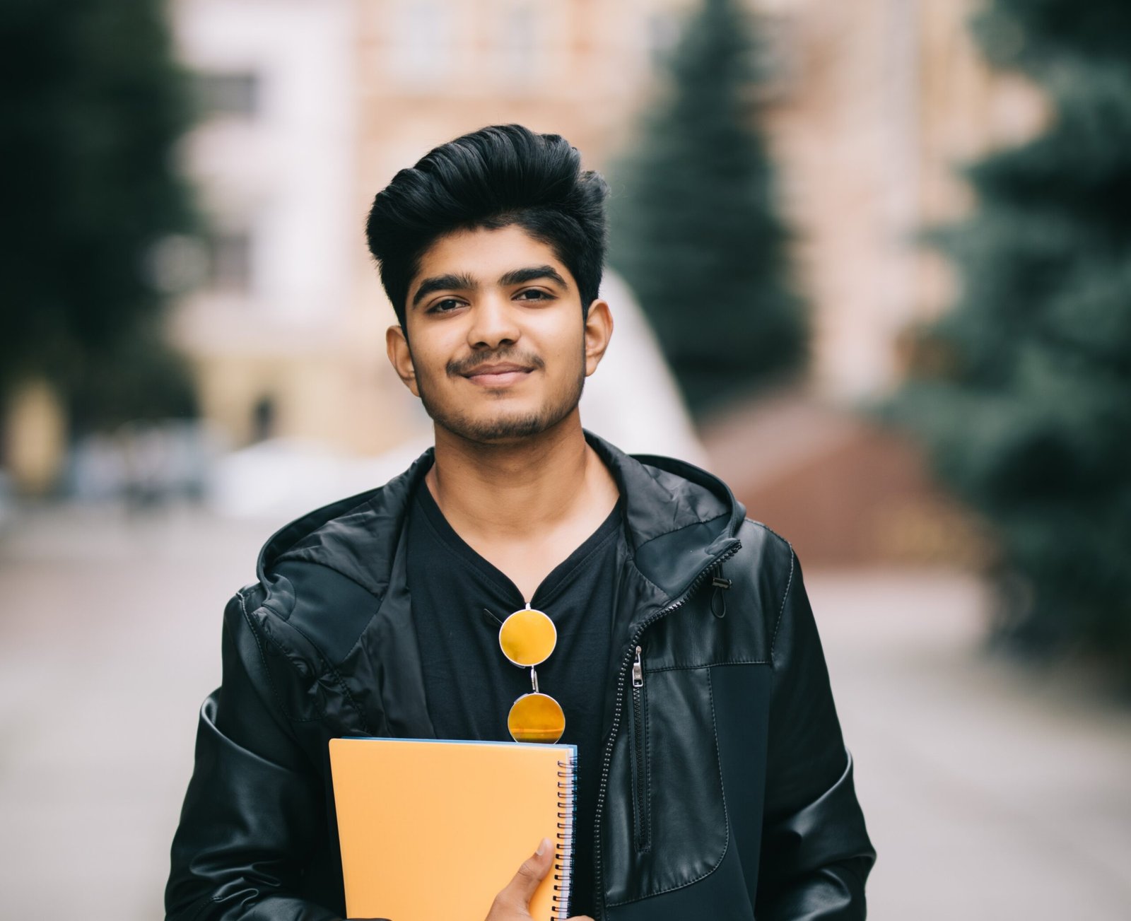Handsome young indian student man read notebooks while standing on the street